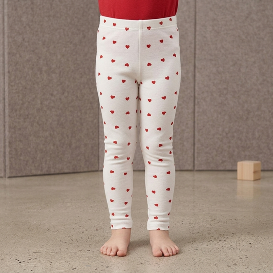 White leggings with red heart patterns worn by a child against a neutral background