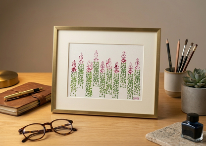 Framed artwork of a floral pattern on a desk with stationery items.