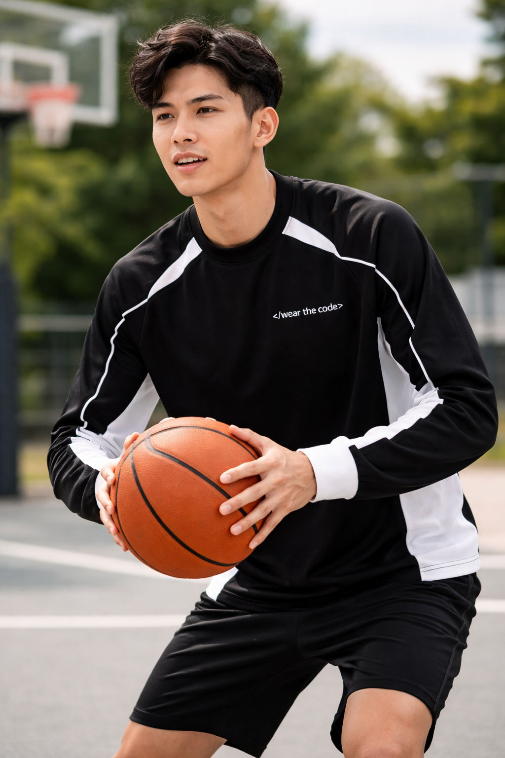 Person holding a basketball on an outdoor court with trees in the background